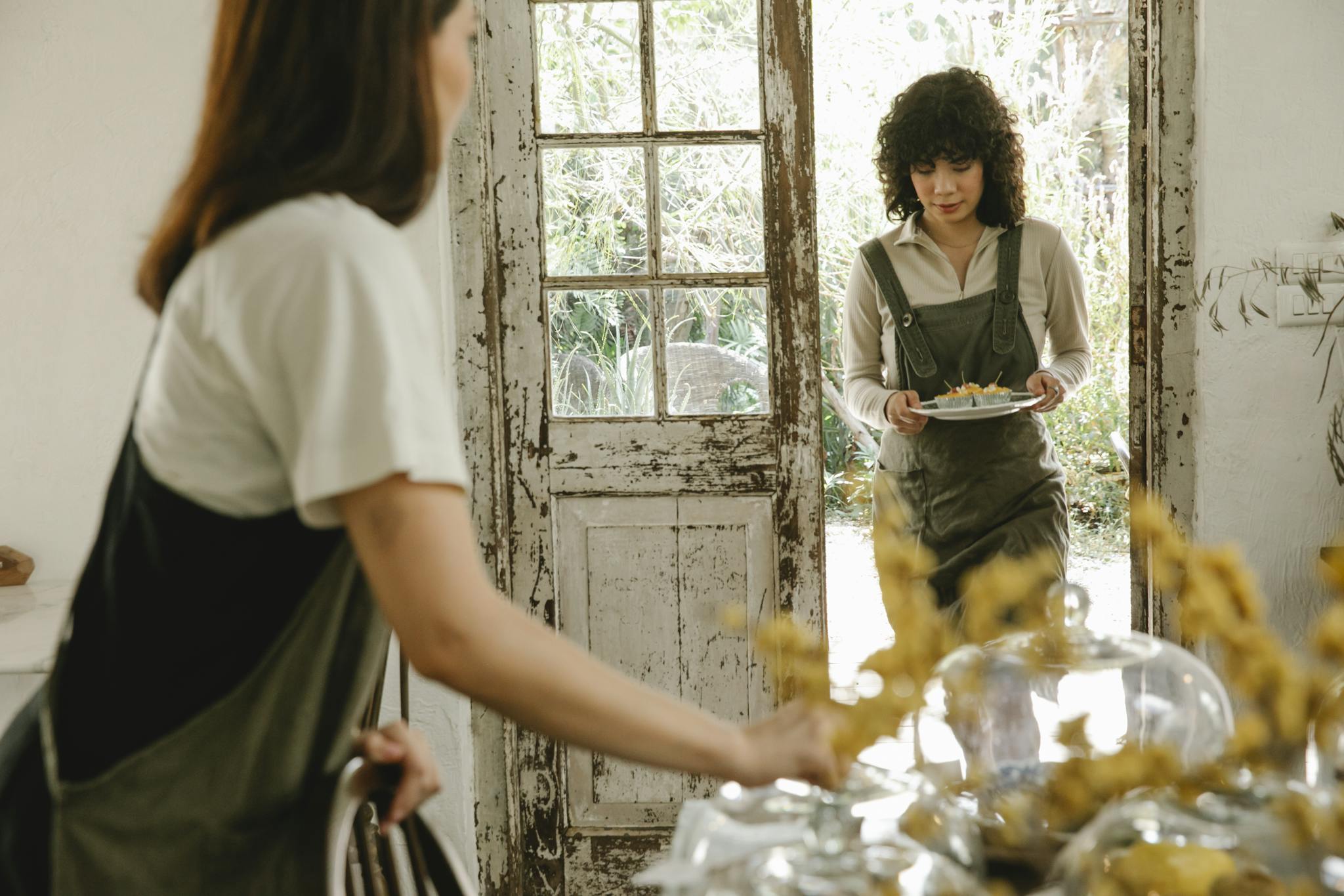 Young female cafe worker wearing apron with plate with delicious desserts in vintage cafe